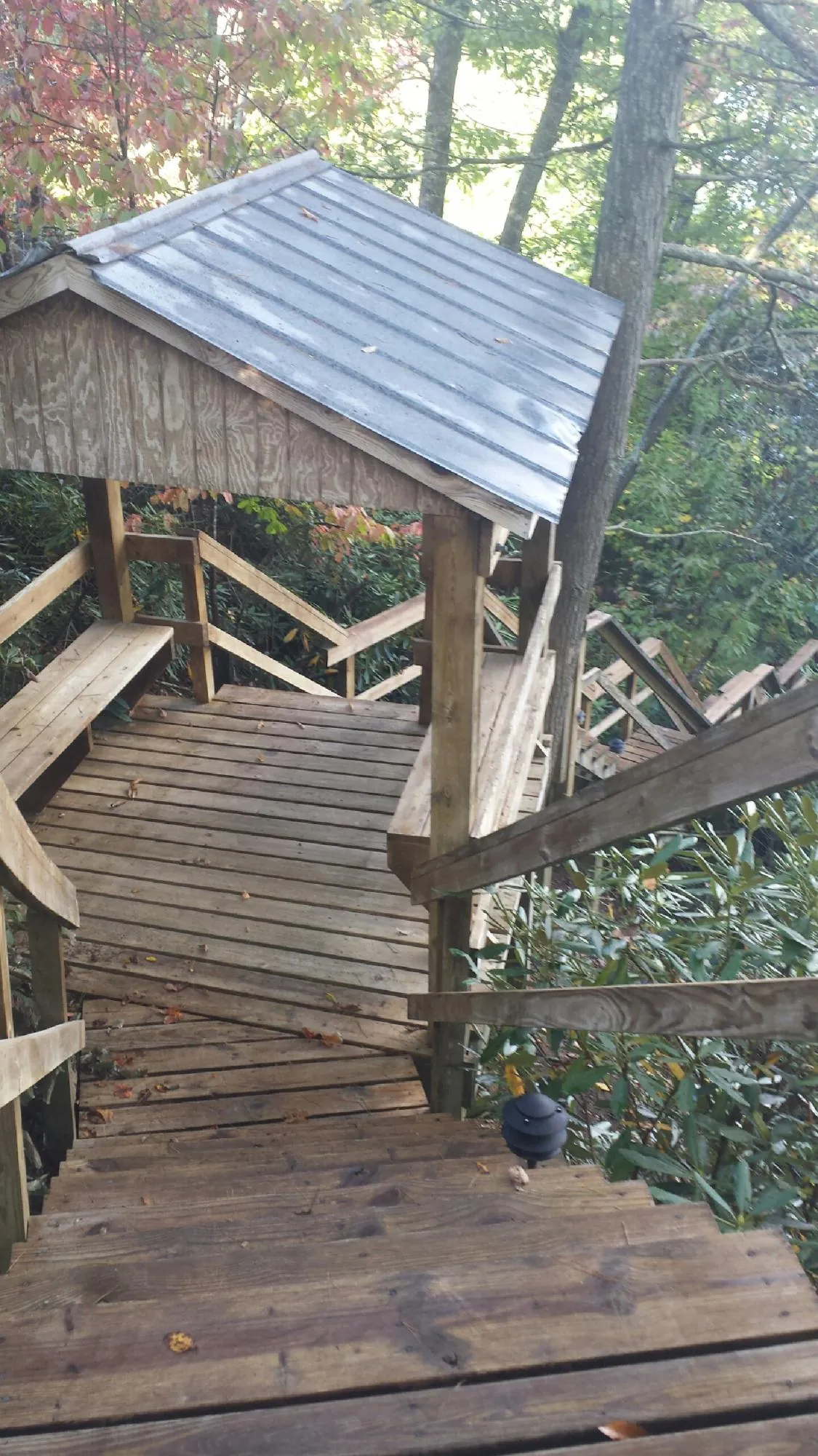 Metal roofed shelter over wooden steps on a wooded walkway — Skylight Repair & Installation work by our crew in Lancaster